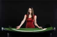 A live dealer in a red dress behind a blackjack table.