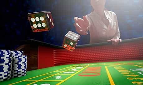 A person rolling a pair of dice in a game of craps.