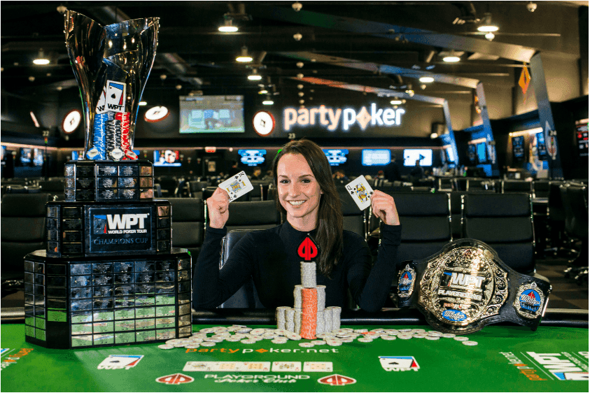 Ema Zajmovic sitting behind a poker table. On the table is her victory belt and playing cards.