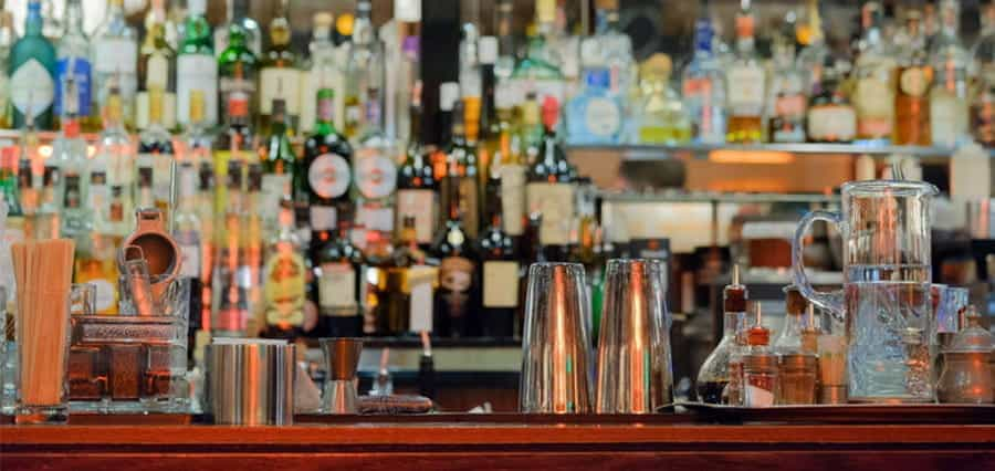 A shelf filled with differnt drinks and cocktail-making equipment.