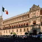 A long view of the Mexico government building, with Mexico’s flag flying in front.