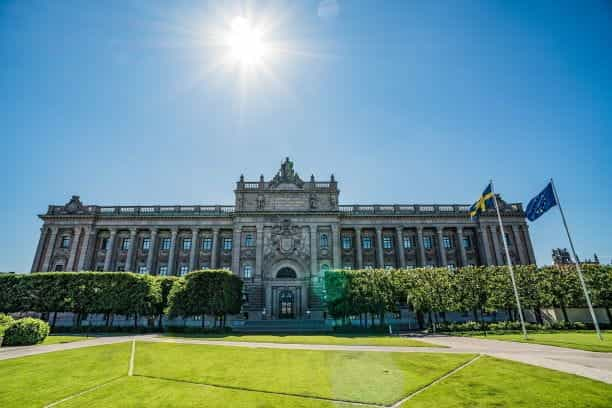 A palace in Sweden with the Swedish flag flying outside.