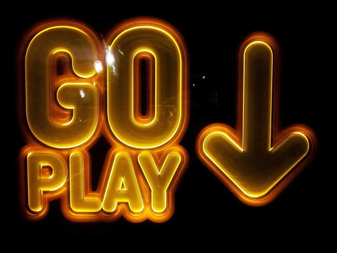 A glowing yellow neon sign reads 'GO PLAY' against a dark backdrop.