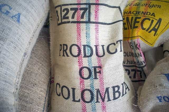 A stack of burlap sacks, with the frontmost labelled PRODUCT OF COLOMBIA.