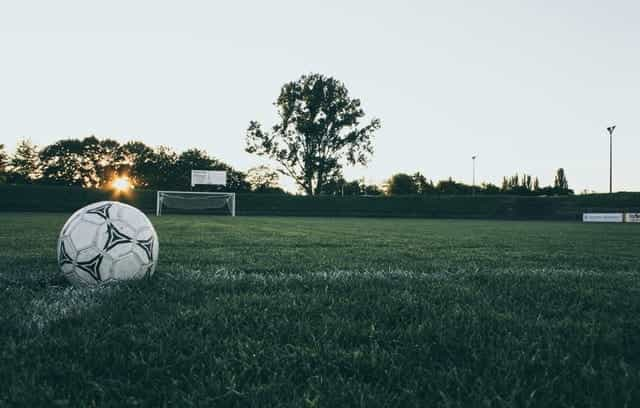 A football and a goal on an empty football field.