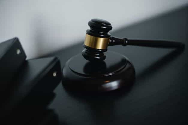 A black wooden gavel sits on a sound block.