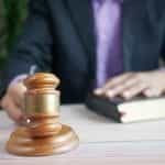 A man in a suit with a book and a gavel.