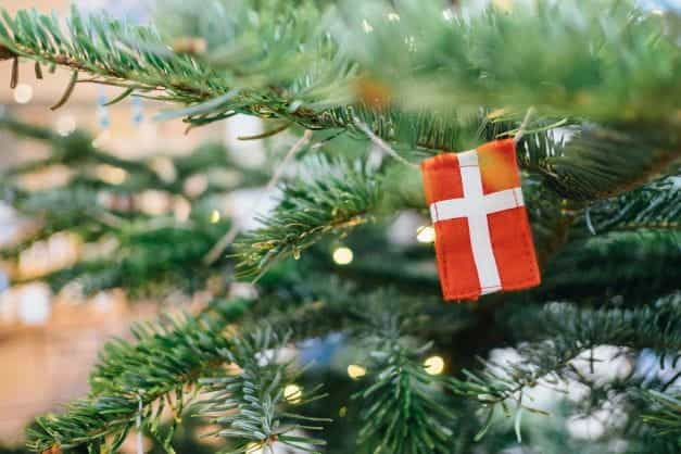 A miniature Denmark flag hangs off a Christmas tree.