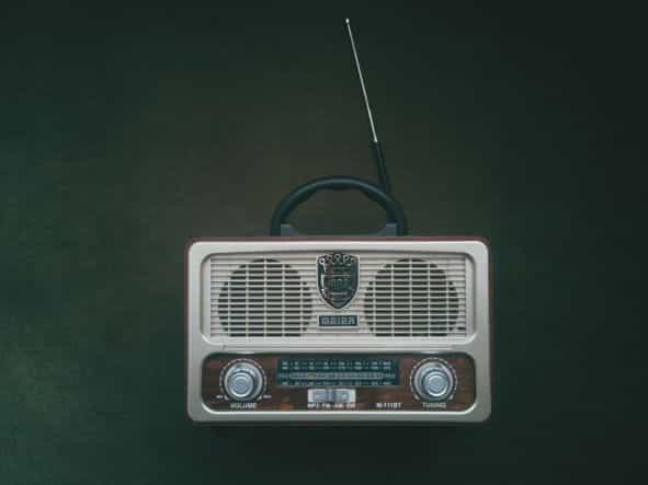 A white and brown radio player placed against a green backdrop.