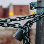 A heavy lock and chain keep a gate closed.