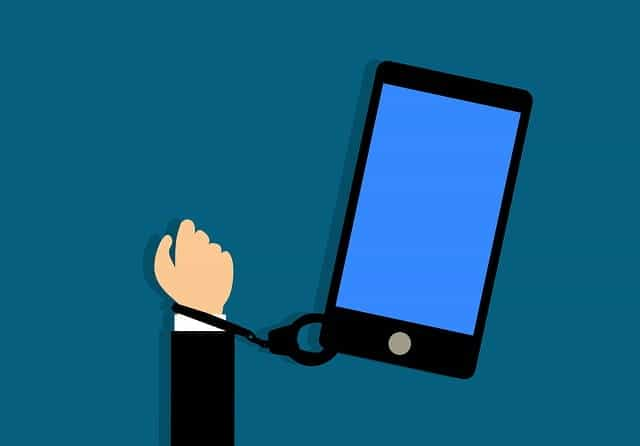 A person’s arm handcuffed to a large smartphone.