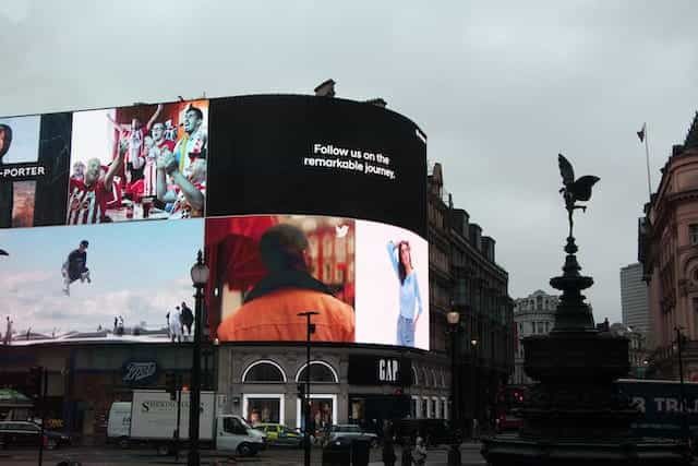 A corner of a building with large, lit advertisement displays.