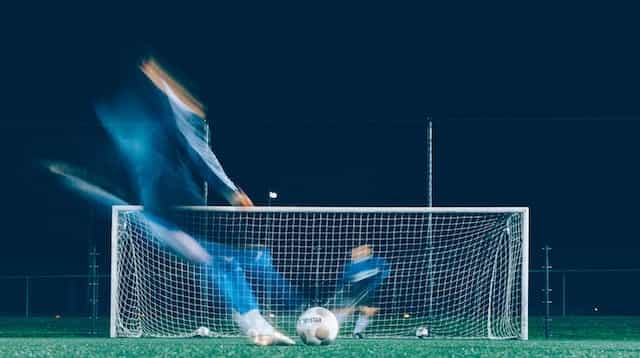 A timelapse photo of a player attempting a kick into a soccer goal.