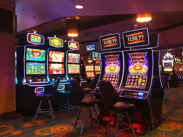 Several brightly lit slot machines in a casino room.