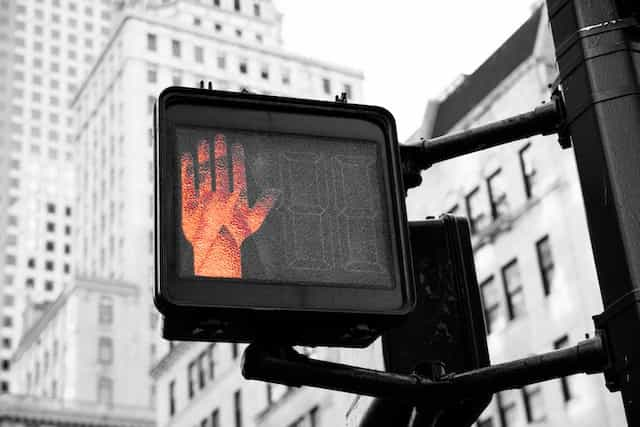 A traffic crossing illuminates a red hand to indicate stopping.