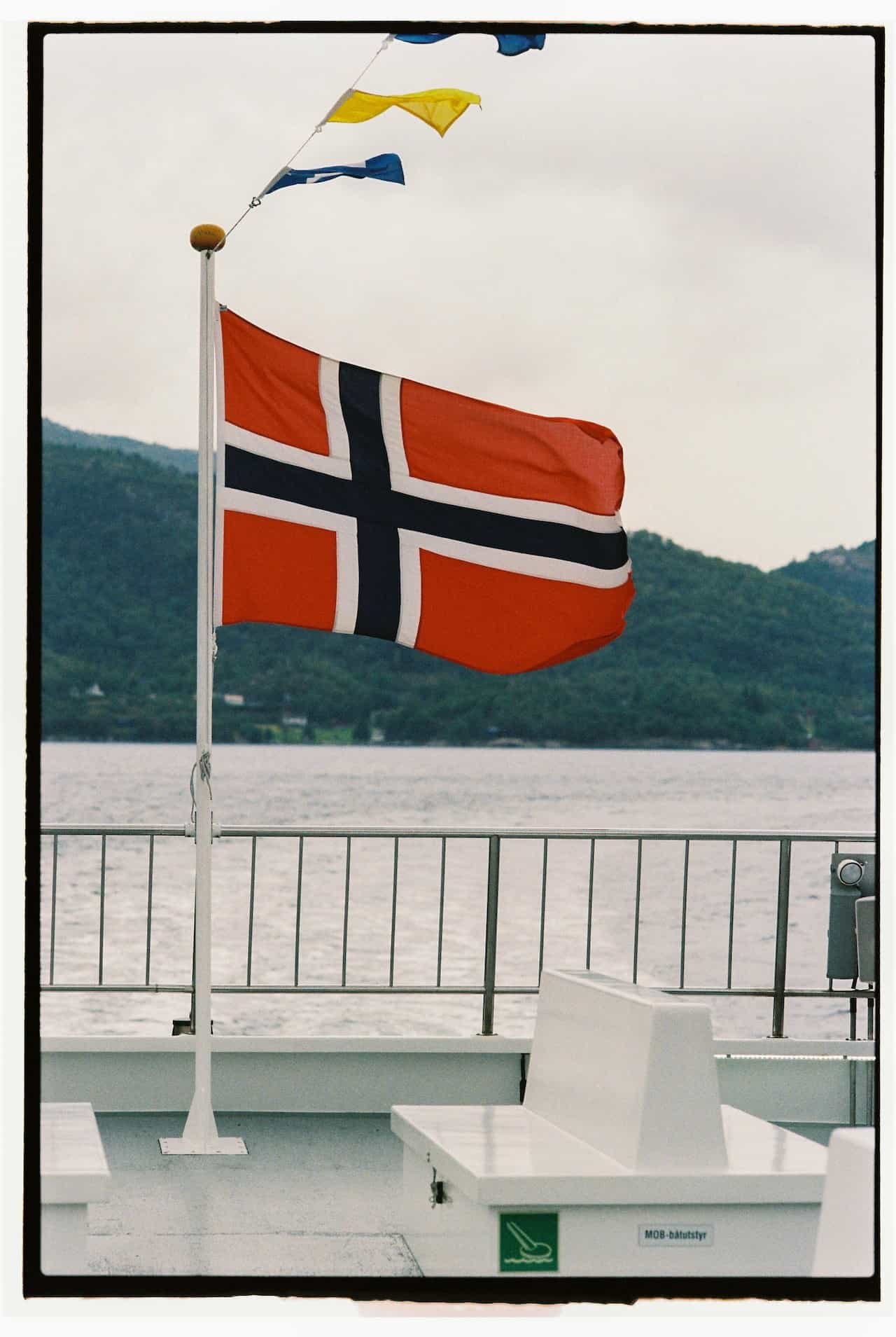 A flag hoisted on a deck near water.