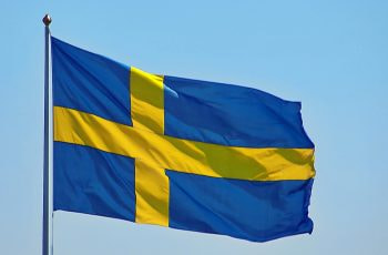 An unfurled flag in the wind against a blue sky.