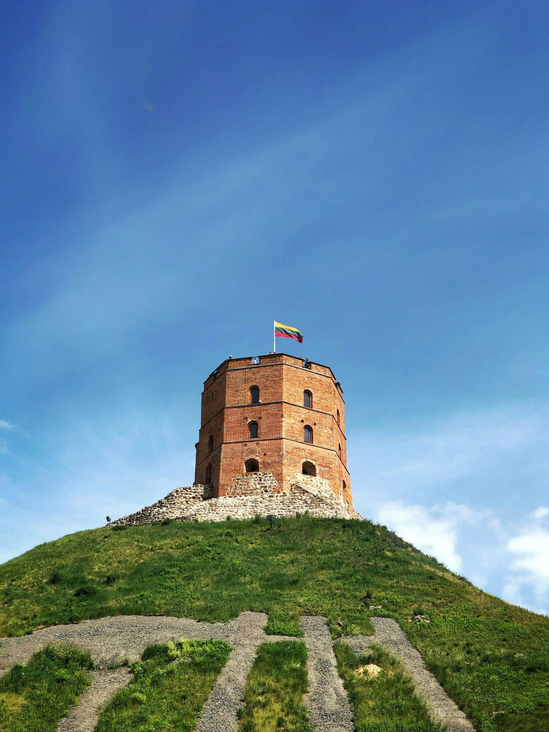 A tall brick tower on top of a grassy hill.