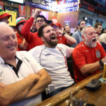 Football fans excitedly watching a game in a pub.